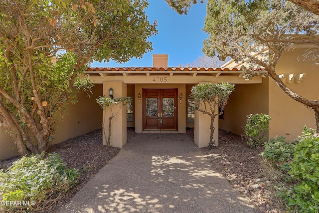 property entrance featuring french doors, a tile roof, and stucco siding