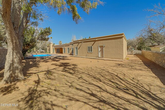 rear view of property with a patio area, fence, a fenced in pool, and stucco siding