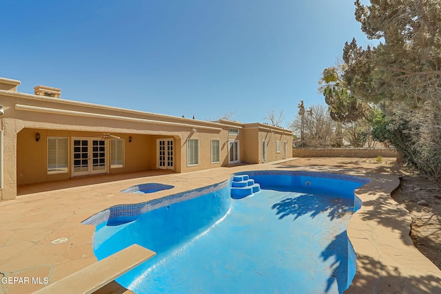 view of swimming pool featuring a fenced in pool, french doors, a patio area, a ceiling fan, and a diving board