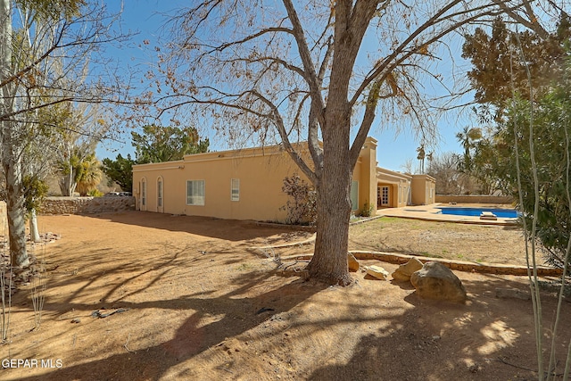 rear view of house featuring stucco siding and a covered pool