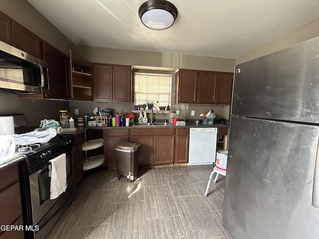 kitchen featuring dark countertops, stainless steel appliances, dark brown cabinets, open shelves, and a sink