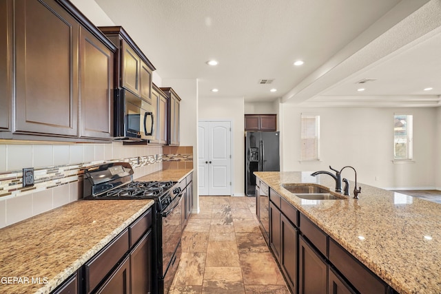 kitchen featuring black appliances, sink, light stone countertops, tasteful backsplash, and dark brown cabinets