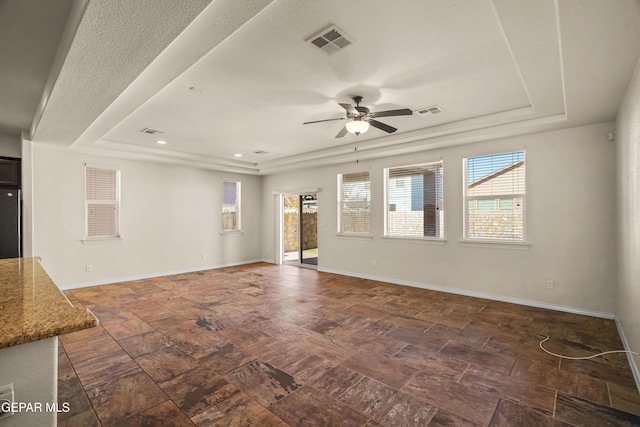 spare room featuring a raised ceiling and ceiling fan