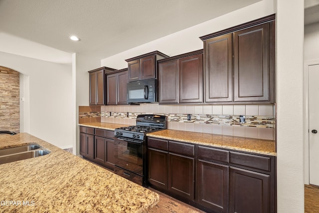 kitchen featuring black appliances, sink, tasteful backsplash, dark brown cabinets, and light stone counters