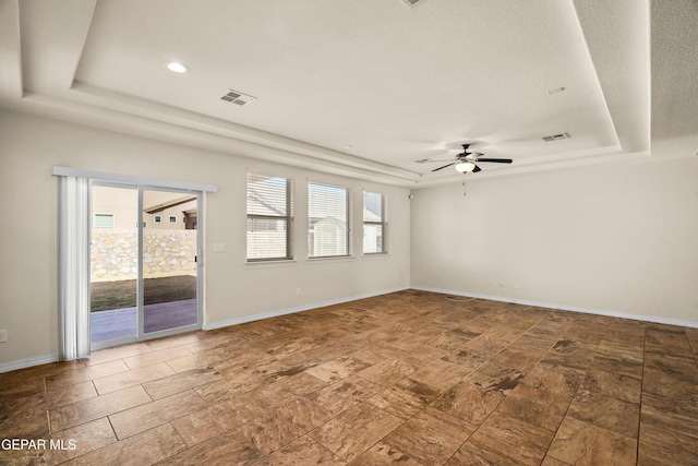 empty room featuring a textured ceiling, a tray ceiling, and ceiling fan