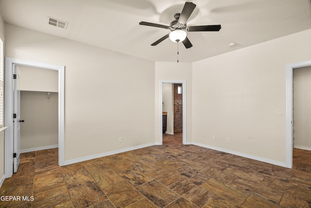 unfurnished bedroom featuring a walk in closet, a closet, and ceiling fan