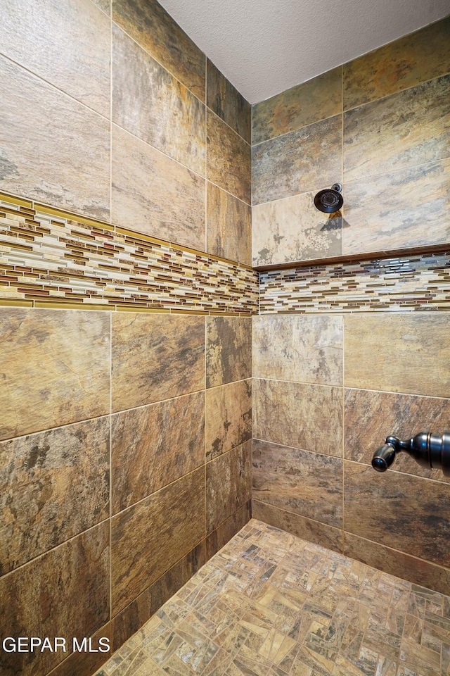 bathroom with a textured ceiling and tiled shower