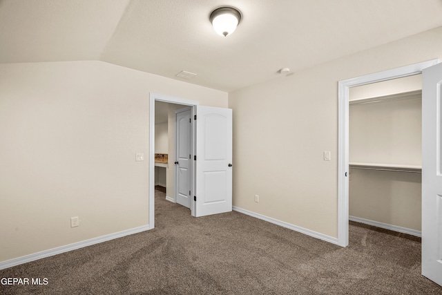 unfurnished bedroom featuring dark carpet, vaulted ceiling, and a closet