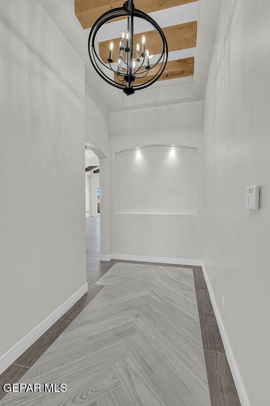 interior space with beamed ceiling and a chandelier