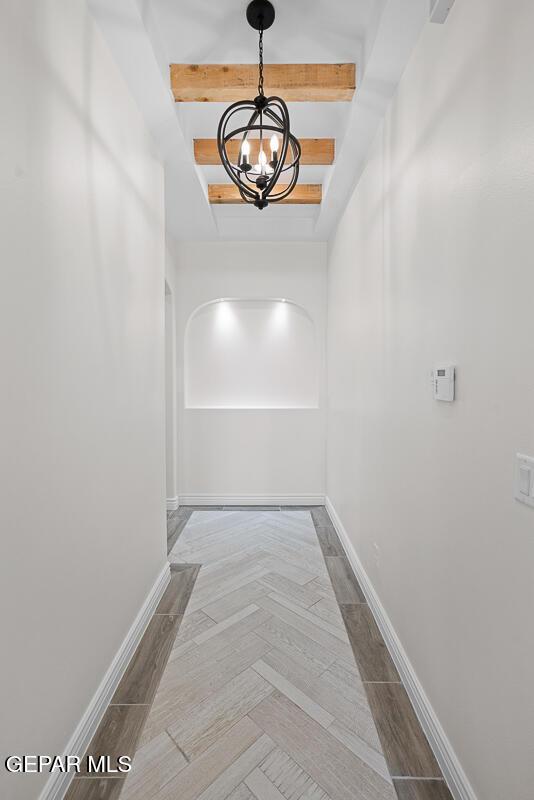 corridor featuring an inviting chandelier and beam ceiling