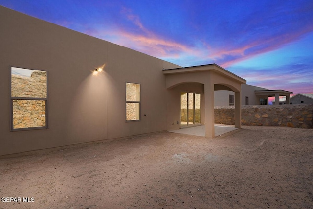 back house at dusk featuring a patio area