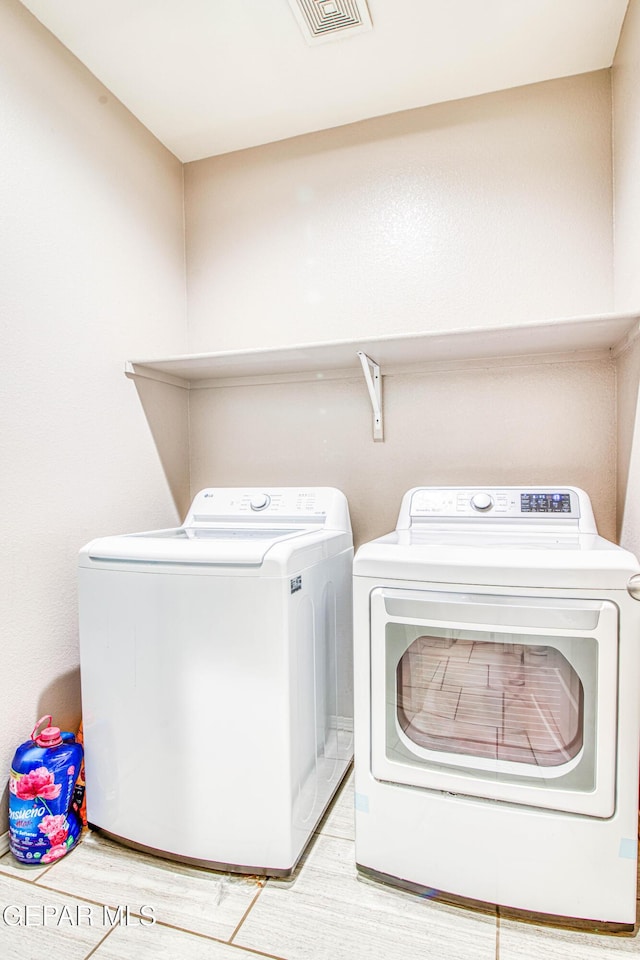 laundry room with washing machine and dryer and light wood-type flooring