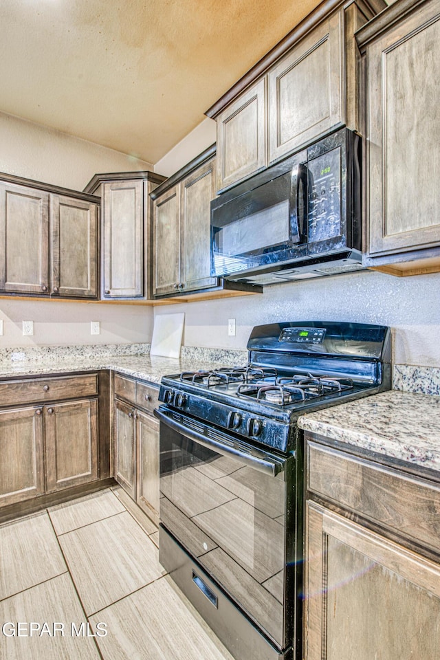 kitchen with black appliances, light tile patterned flooring, and light stone counters