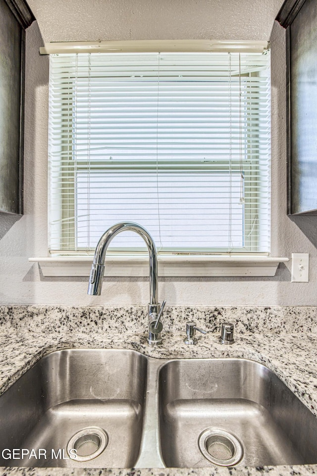 interior details with light stone countertops, dark brown cabinetry, and sink