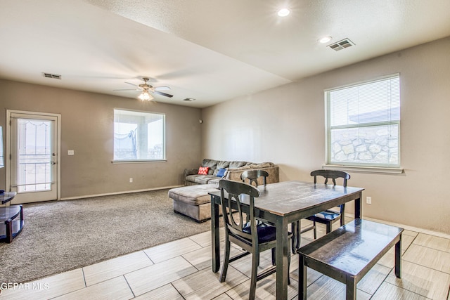 dining space with ceiling fan, a healthy amount of sunlight, and light colored carpet