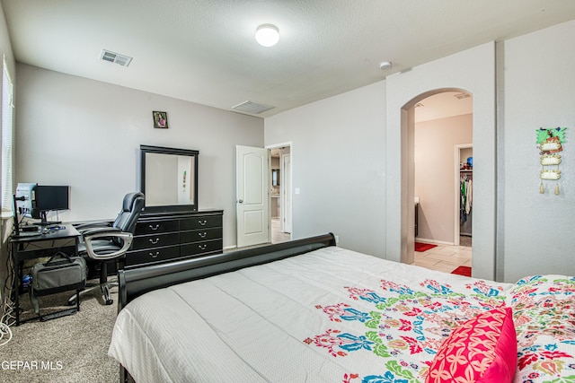 bedroom featuring light colored carpet, a textured ceiling, and ensuite bath