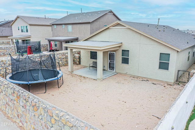 rear view of house with a trampoline and a patio