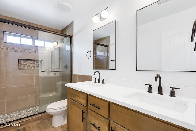 bathroom featuring wood-type flooring, vanity, toilet, and a shower with door