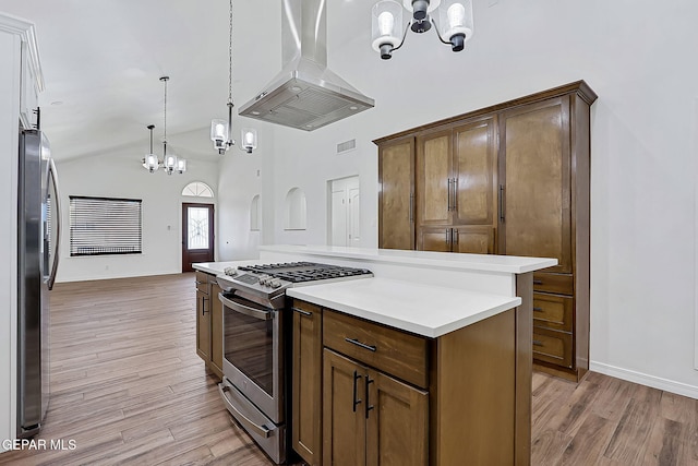 kitchen with pendant lighting, island range hood, stainless steel appliances, and light hardwood / wood-style floors