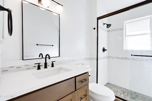 bathroom featuring a tile shower, vanity, and toilet