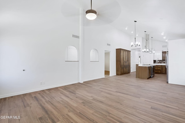 unfurnished living room featuring ceiling fan, high vaulted ceiling, and light wood-type flooring