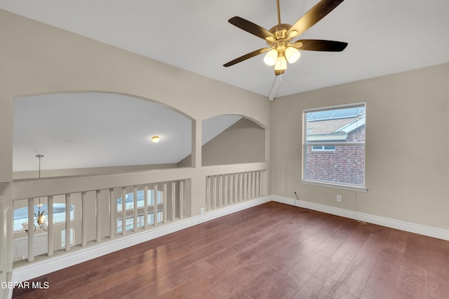 empty room featuring dark hardwood / wood-style flooring, vaulted ceiling, and ceiling fan