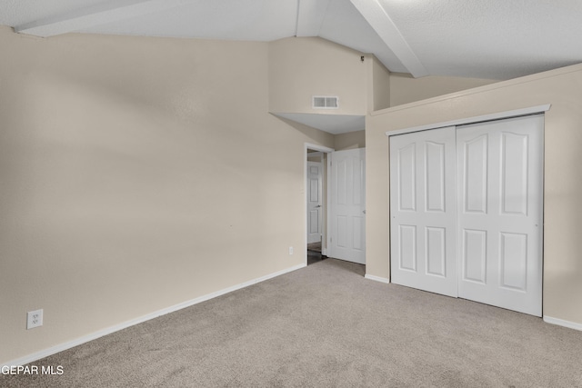 unfurnished bedroom with light colored carpet, vaulted ceiling, and a closet