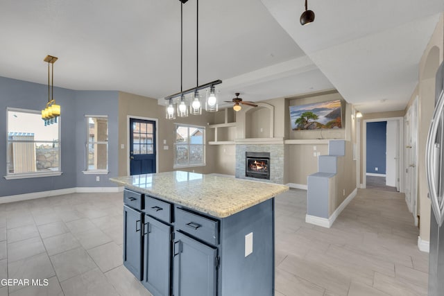 kitchen with pendant lighting, a kitchen island, ceiling fan, and a healthy amount of sunlight