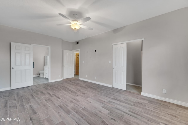 unfurnished bedroom featuring ceiling fan, light hardwood / wood-style floors, a closet, and ensuite bath