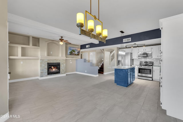 kitchen featuring a center island, tasteful backsplash, pendant lighting, white cabinets, and appliances with stainless steel finishes