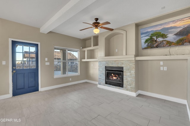 unfurnished living room featuring ceiling fan, a fireplace, and beamed ceiling