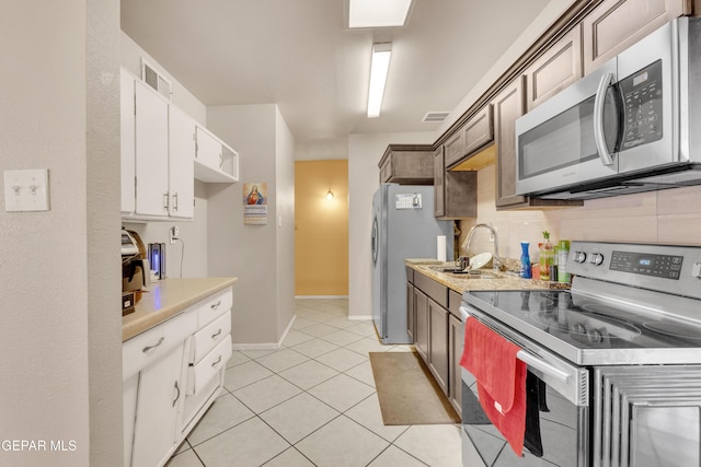 kitchen with sink, light tile patterned floors, appliances with stainless steel finishes, dark brown cabinets, and white cabinetry