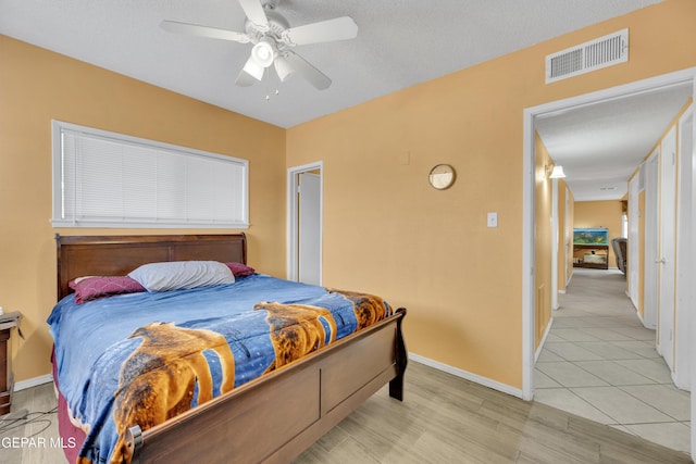 bedroom with a textured ceiling, light hardwood / wood-style flooring, and ceiling fan