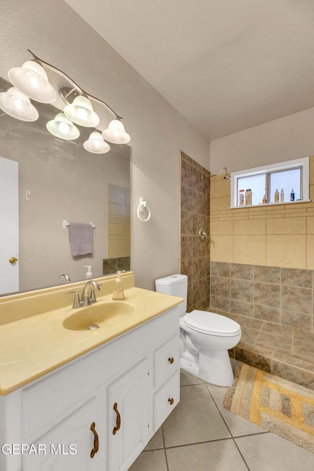 bathroom featuring tile patterned floors, vanity, tiled shower, and toilet