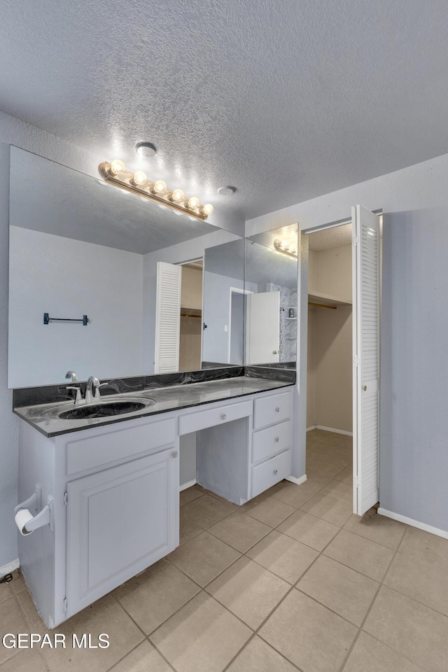 bathroom with tile patterned floors, vanity, and a textured ceiling