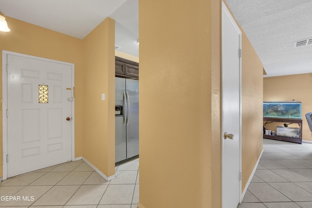 entryway with light tile patterned floors and a textured ceiling