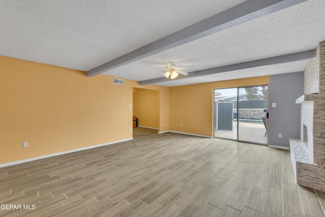 unfurnished living room featuring a textured ceiling, ceiling fan, beam ceiling, light hardwood / wood-style flooring, and a fireplace