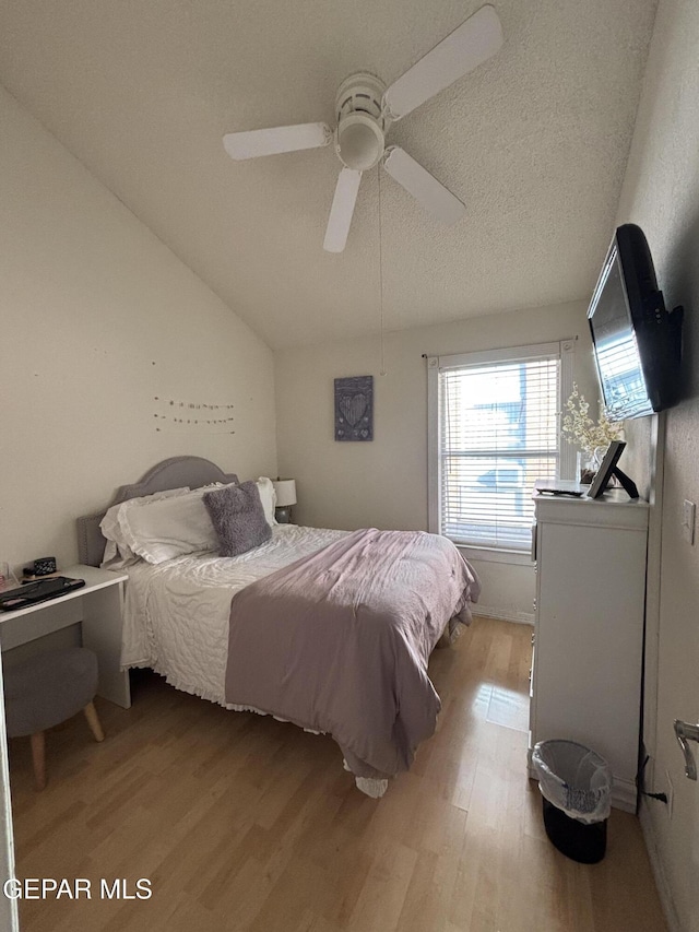 bedroom featuring ceiling fan, light wood-type flooring, a textured ceiling, and vaulted ceiling