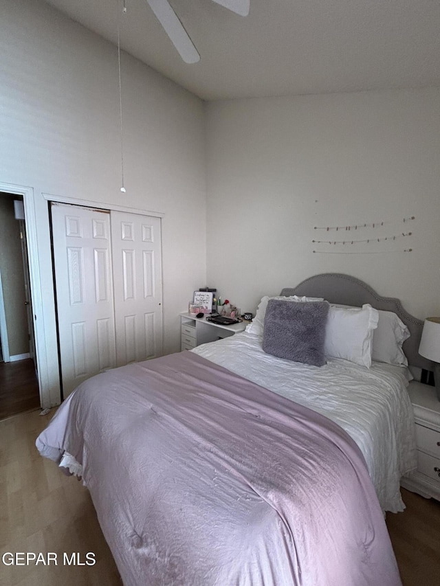 bedroom featuring hardwood / wood-style floors, a closet, high vaulted ceiling, and ceiling fan