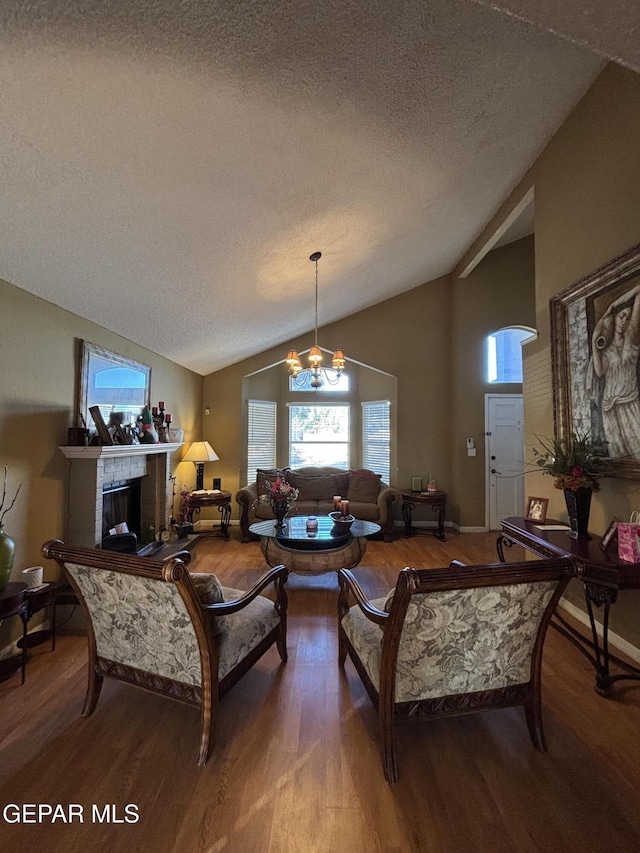 living room featuring a textured ceiling, a chandelier, vaulted ceiling, and hardwood / wood-style flooring