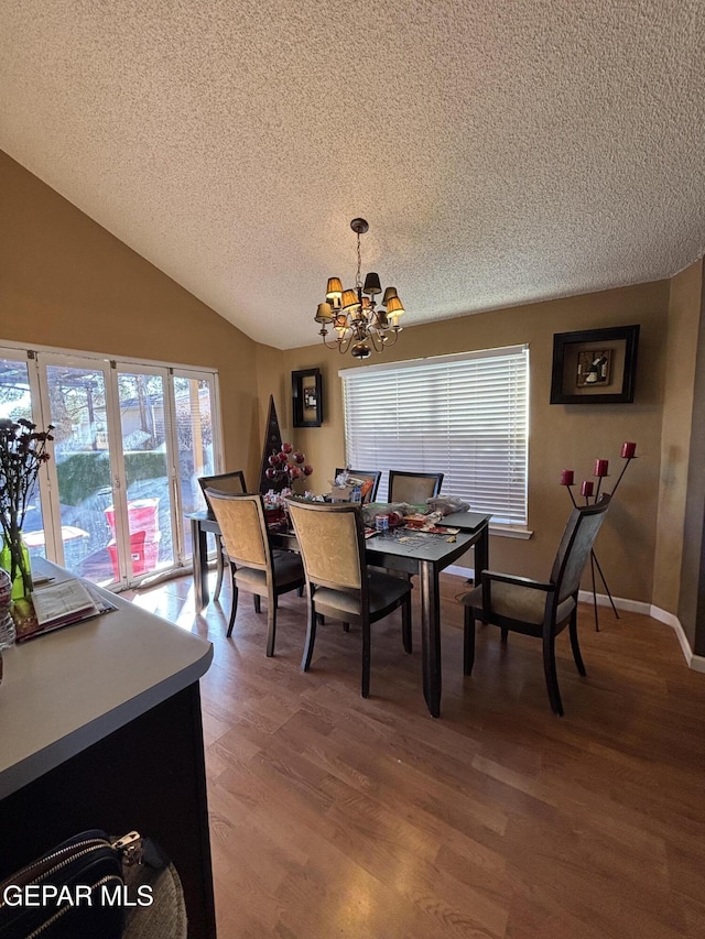 dining area with a textured ceiling, an inviting chandelier, vaulted ceiling, and hardwood / wood-style flooring