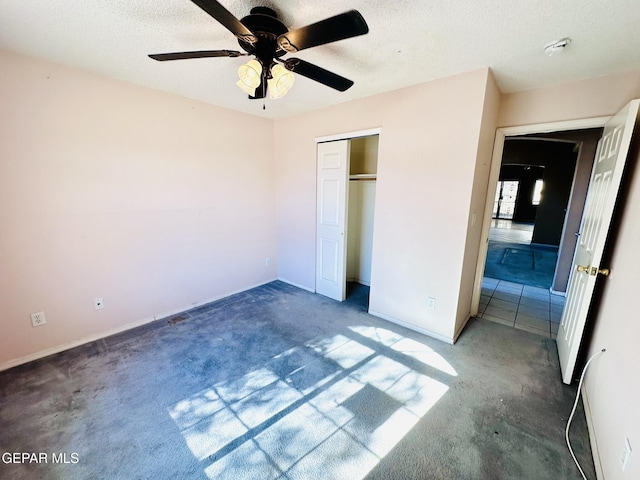 unfurnished bedroom with a textured ceiling, dark carpet, a closet, and ceiling fan