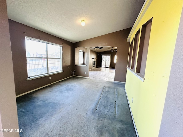 carpeted spare room with ceiling fan and a textured ceiling