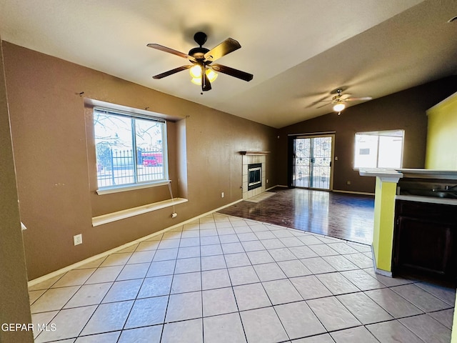 interior space featuring a wealth of natural light, a fireplace, vaulted ceiling, and light wood-type flooring