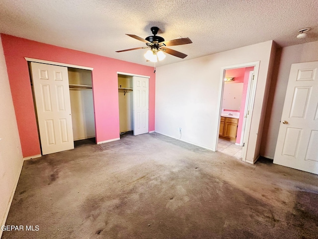 unfurnished bedroom with a textured ceiling, carpet floors, ensuite bathroom, and ceiling fan