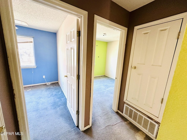 hallway with carpet flooring and a textured ceiling