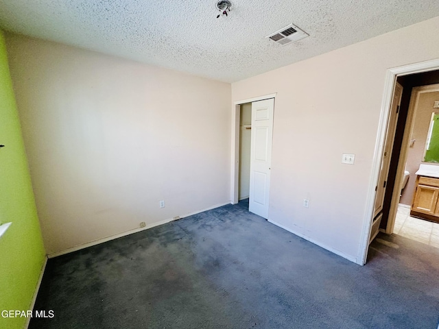 unfurnished bedroom featuring a closet, a textured ceiling, and dark colored carpet