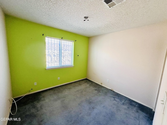 spare room with dark colored carpet and a textured ceiling