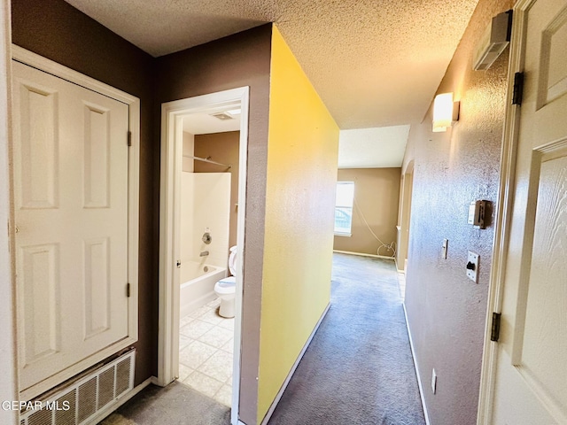 hall featuring light carpet and a textured ceiling