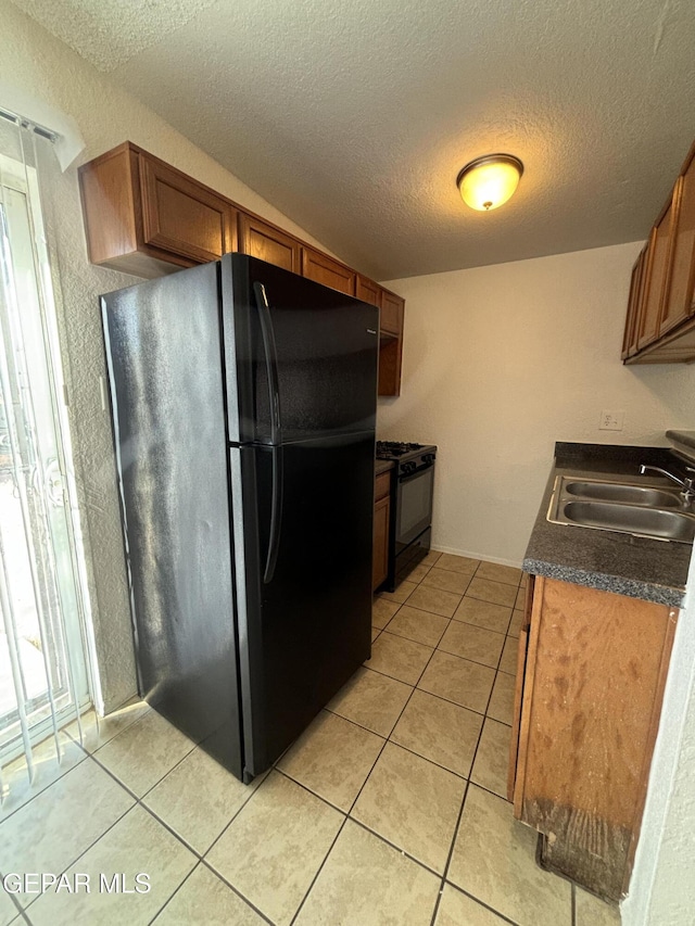 kitchen with black appliances, light tile patterned floors, sink, and a textured ceiling